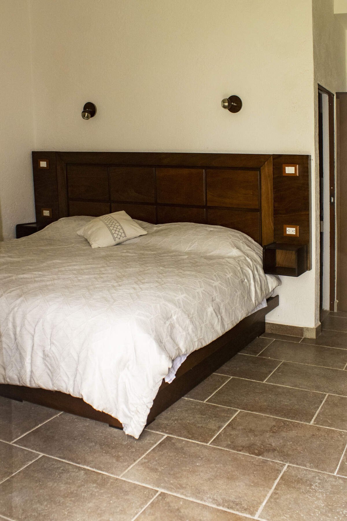 Habitación con cabecera de madera y ropa de cama en tonos grises
