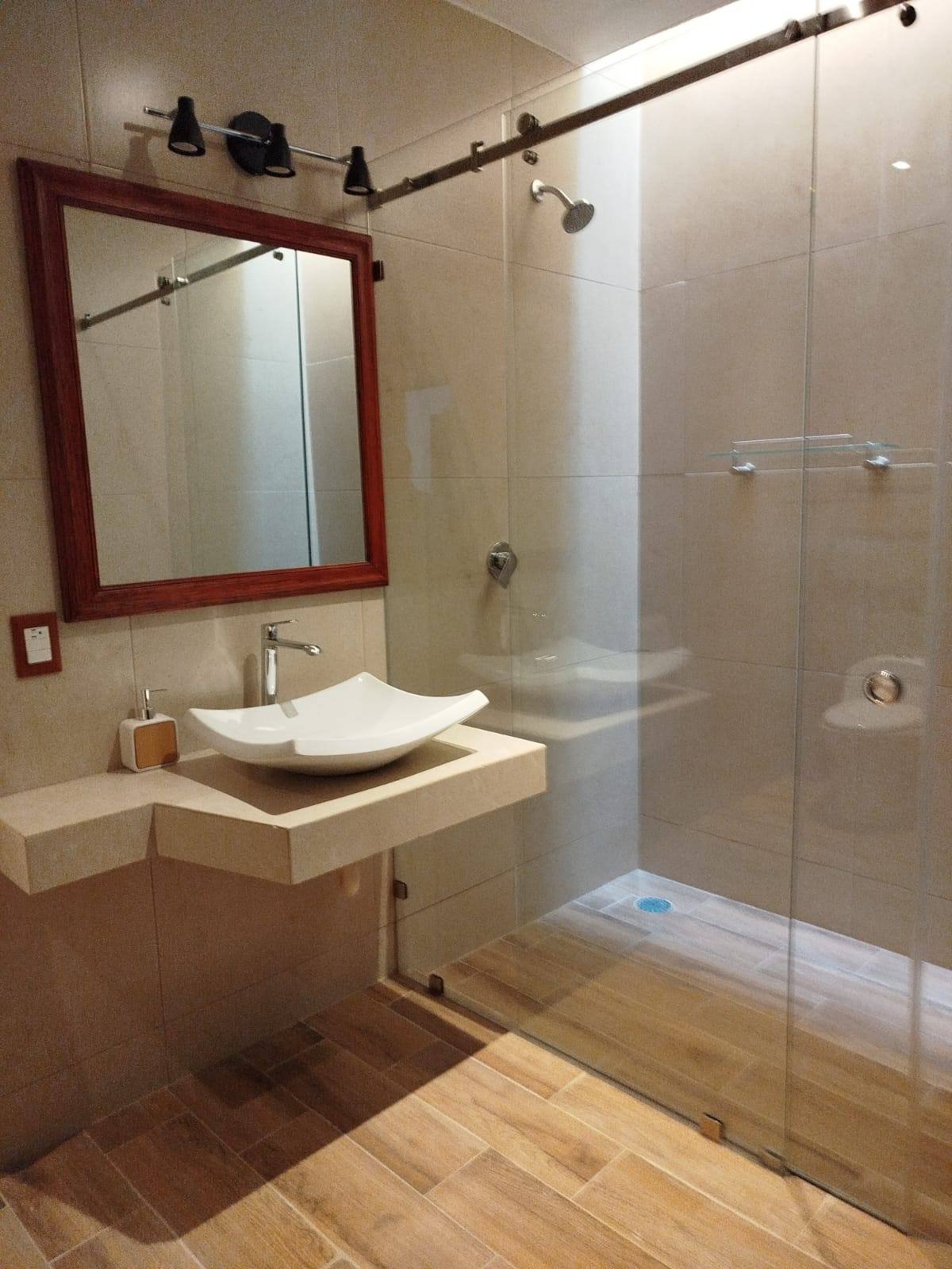 Baño privado con regadera de cristal templado y lavabo de diseño