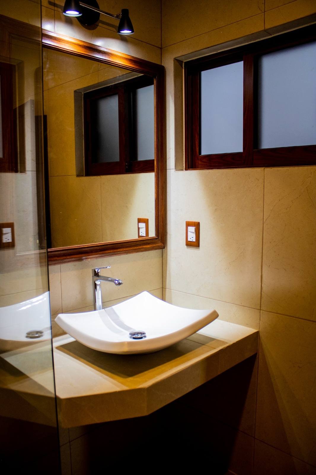 Lavabo de diseño con cubierta de piedra y espejo con marco de madera